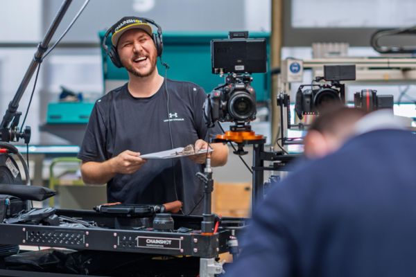 Florian Klaes lacht während eines Videodrehs, umringt von seinem Videoequipment